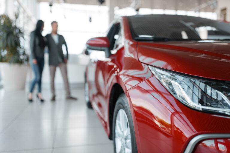 Couple buying new red car in showroom. Male and female customers looks vehicle in dealership, automobile sale, auto purchase